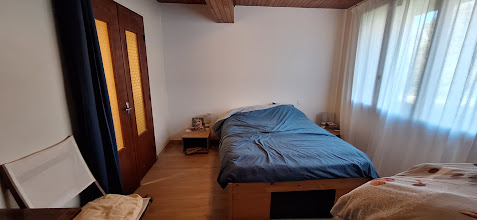 Chambre lumineuse du rez-de-chaussée avec un lit double.